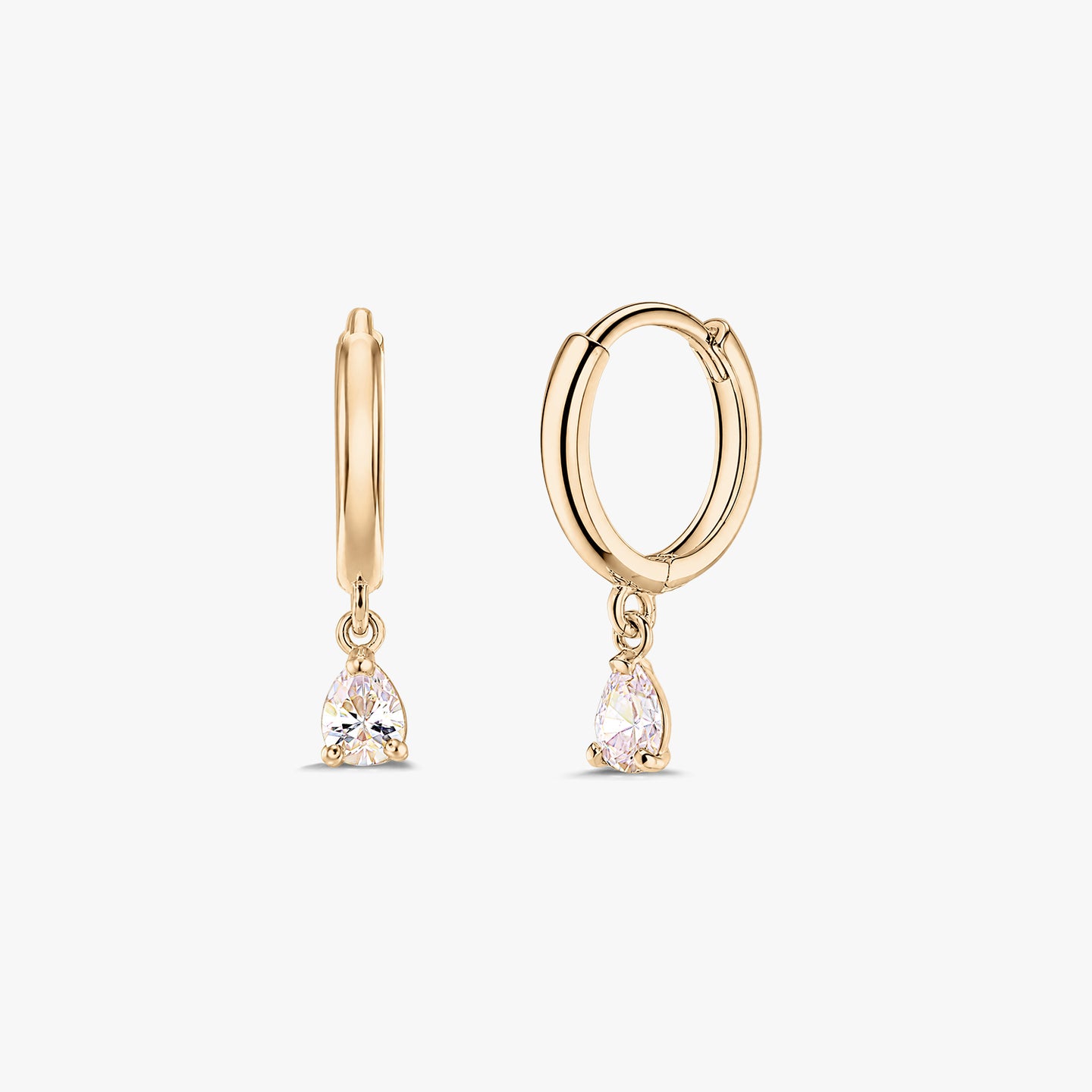 Двойка обеци халки тип huggie от жълто злато 14K с висящи бели цирконии с крушовидна шлифовка, на бял фон.
